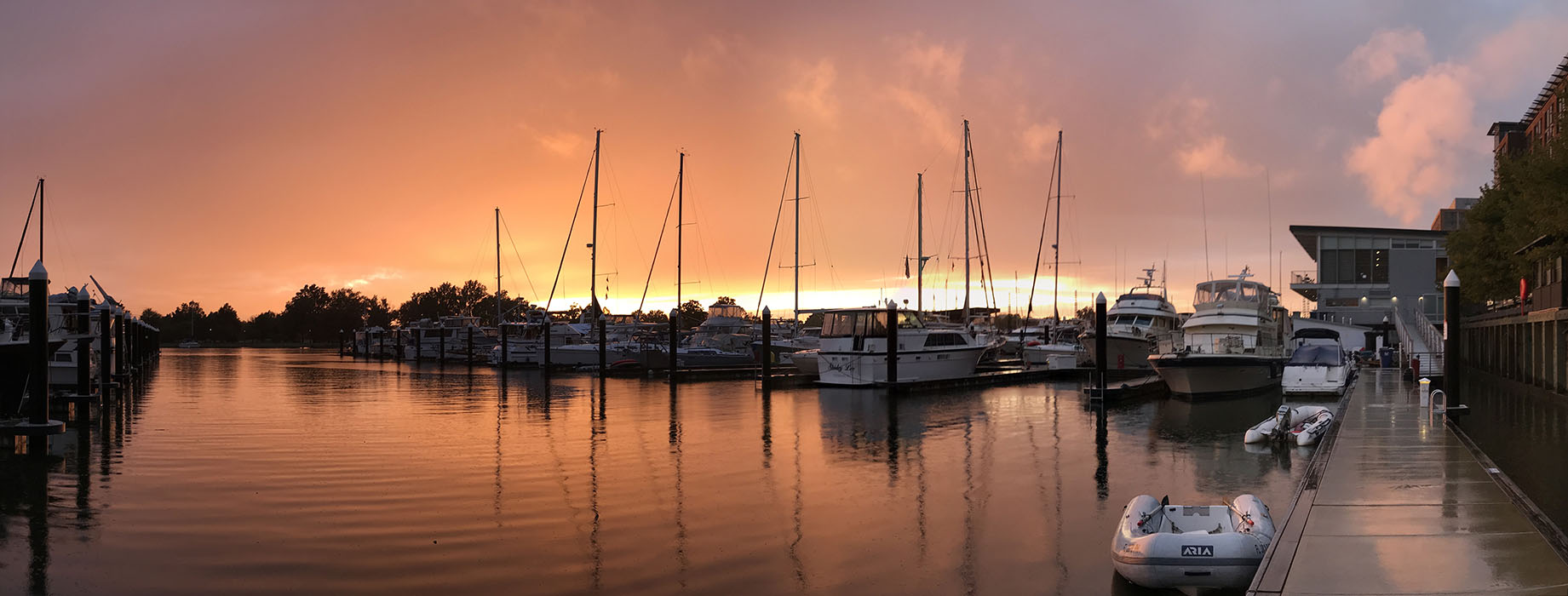 Panorama Red Sunset behind moored boats at yacht basin.
